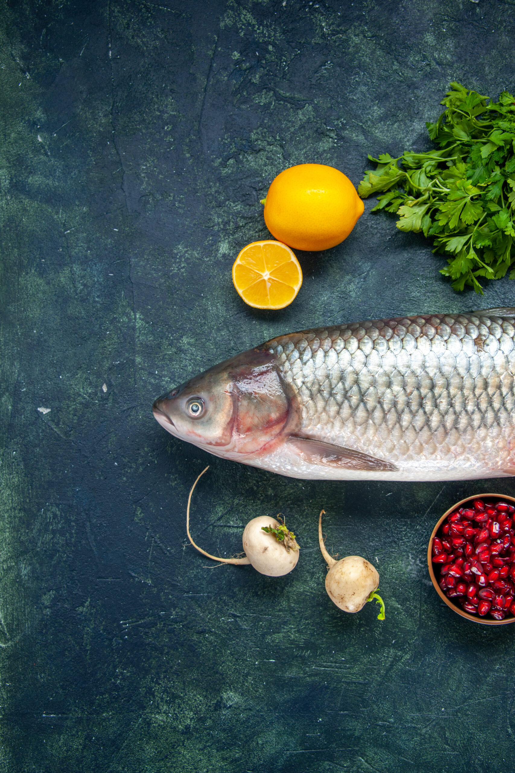 About top view raw fish radish parsley pomegranate small bowl lemon table with free space